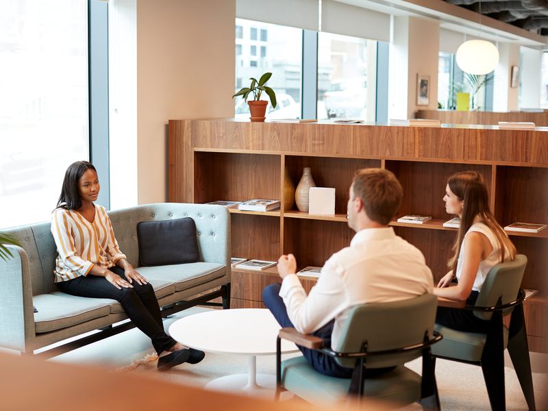Colleagues having a candid conversation in a modern office lounge