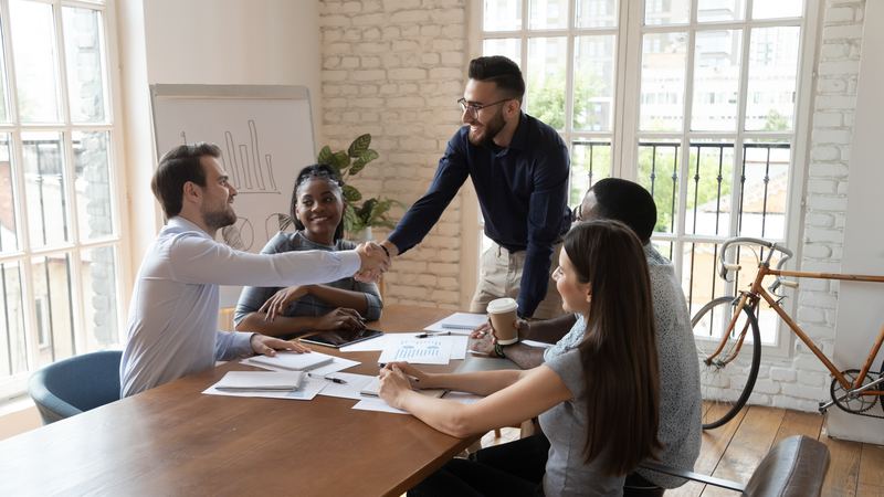Sales and marketing professionals shaking hands after a successful client meeting